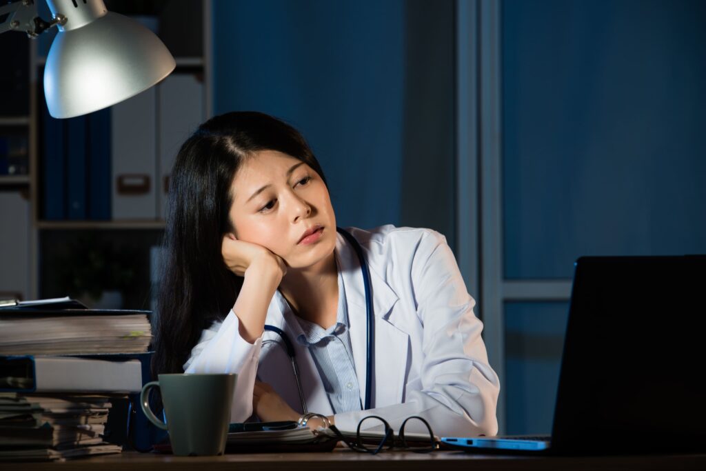 Tired female doctor staring at her screen while working at night