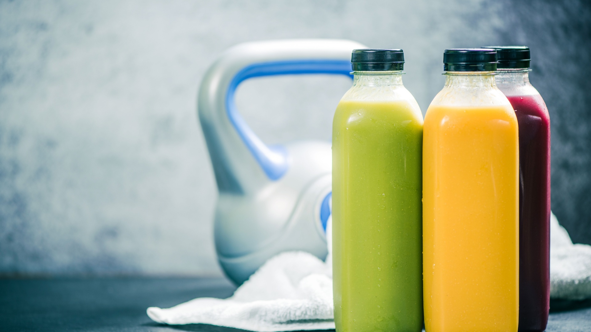 Bottled pre-workout drinks placed in front of a kettlebell and a towel